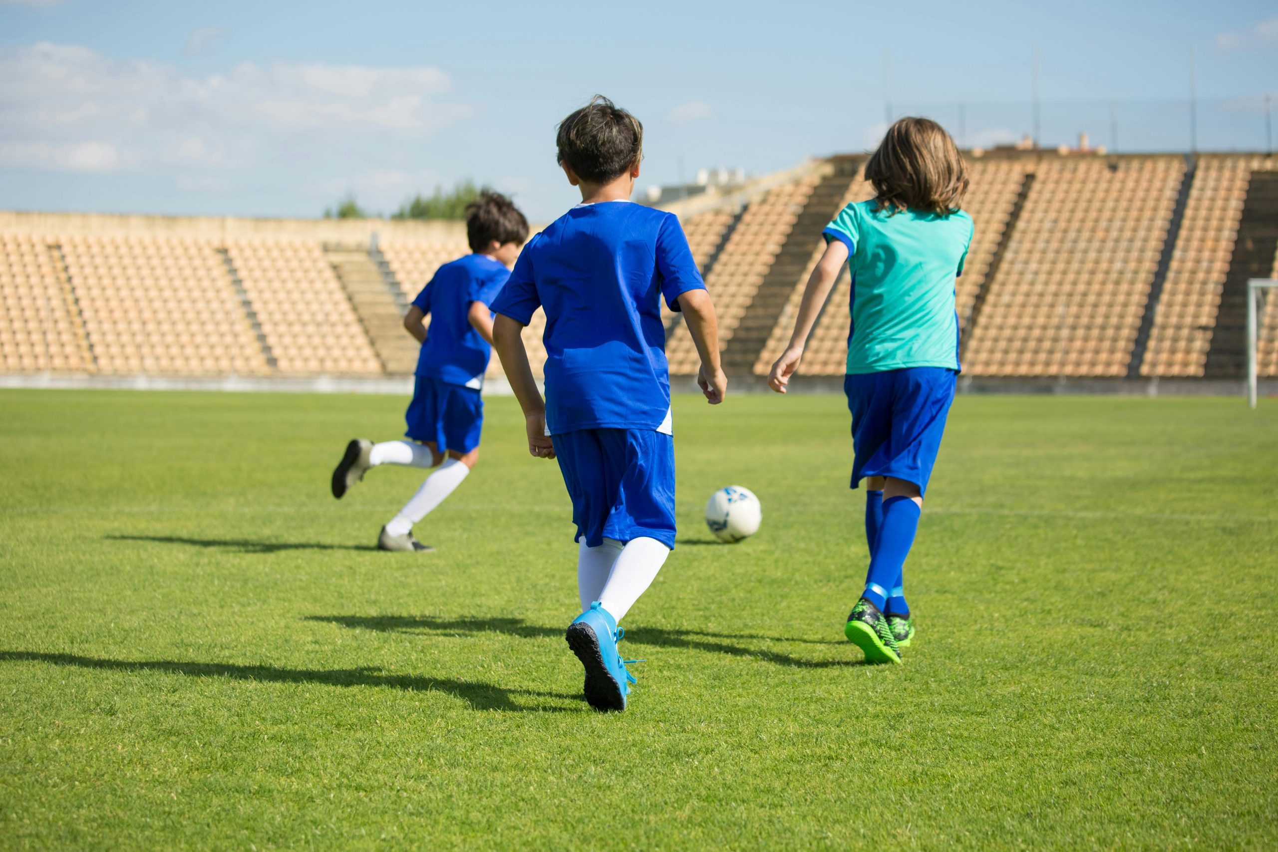 Three kids play soccer on a bright outdoor field, enjoying teamwork and sports.